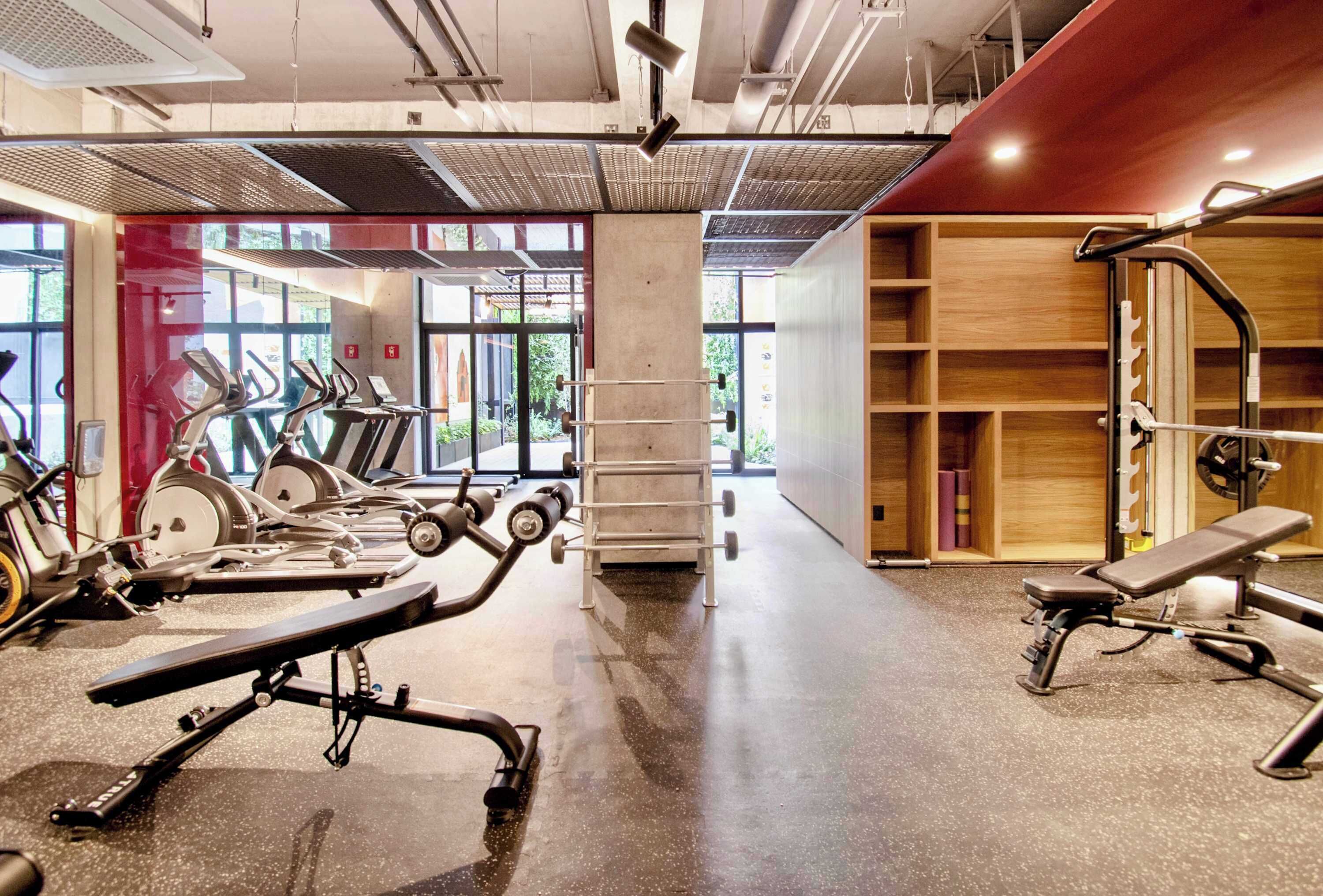 A gym with exercise equipment, a bench, and a wall with shelves.