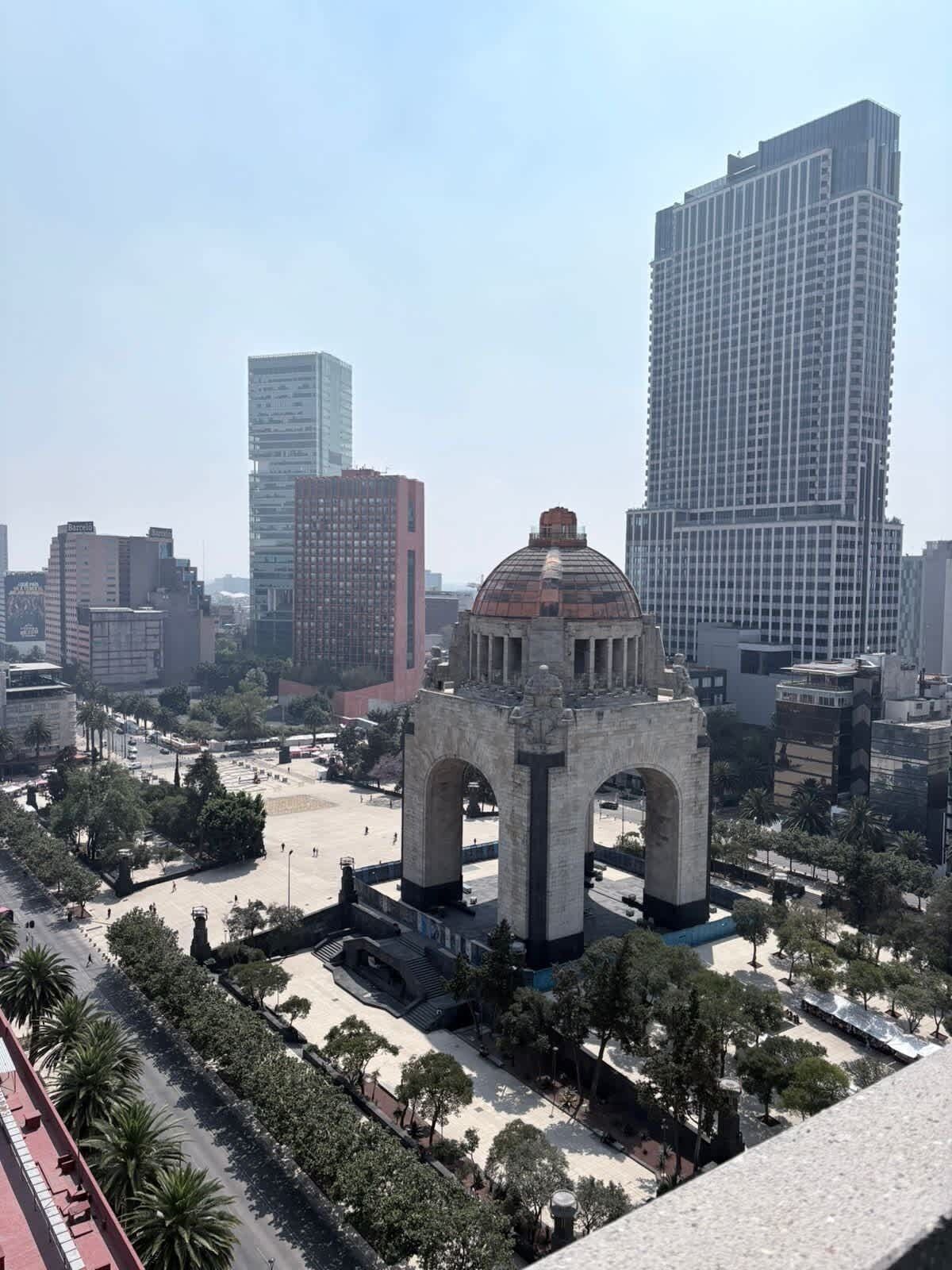 Paesaggio urbano con un imponente monumento ad arco in primo piano, circondato da moderni grattacieli.