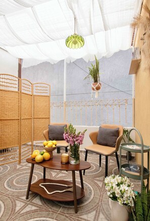 A cozy outdoor seating area with a round table, chairs, and a hanging plant. - Casa Awen - Acogedora Casa en la Roma Norte (Mexico City)