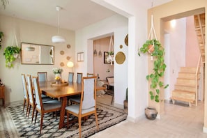 A dining area with a wooden table, chairs, hanging plants, and a staircase. - Casa Awen - Acogedora Casa en la Roma Norte (Mexico City)