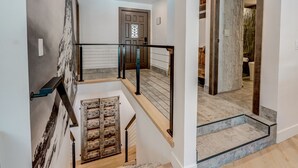 Un interior de varios niveles con escalera, puerta de madera y pared de piedra.