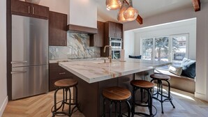 Cocina moderna con una isla grande, electrodomésticos de acero inoxidable y vistas al exterior.