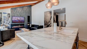 Una cocina moderna con encimera de mármol, horno integrado y un amplio ventanal.