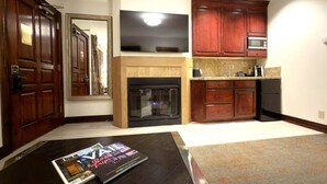 A living room with a fireplace, a television, wooden cabinets, and a kitchen area. - BC Lodge King Suite | Fireplace | Village Location (Beaver Creek)