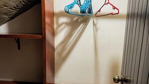 Ein Zimmer mit einer hölzernen Sitzbank, einem Kleiderständer mit blauen und roten Kleiderbügeln und einer Tür mit Messingklinke.