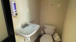 Ein Badezimmer mit Waschbecken, Toilette und Wandseifenspender.