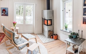 A cozy room with a fireplace, seating, and a view of trees. - Gorgeous home in Alingsås with sauna (Alingsås)