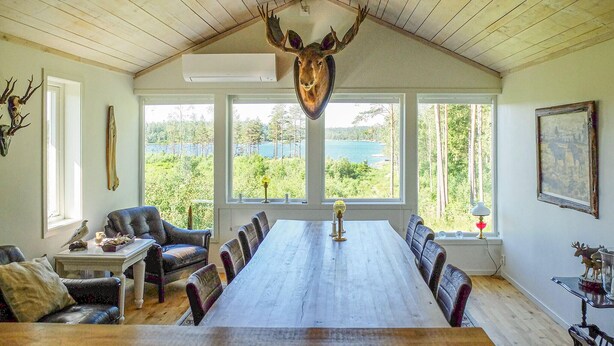 A dining room with a long table, chairs, and a mounted deer head on the ceiling.