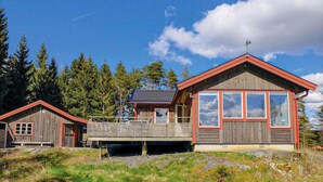 A cabin with a wooden exterior, a balcony, and large windows.