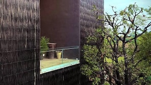 Ein modernes Gebäude mit strukturierter Fassade, einem sichtbaren Fenster und einem Baum im Vordergrund.