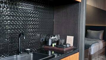 A compact kitchen with a black sink, wooden cabinets, and a patterned backsplash.