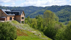 A wooden house with a sloped roof, situated on a hillside with a forested backdrop. - Chalet in a beautiful setting (Albrechtice v Jizerskych horach)