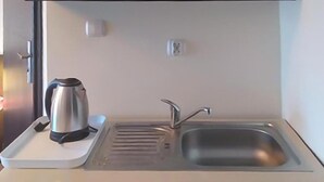 Eine Küchenzeile mit Wasserkocher, Spüle und Steckdose.