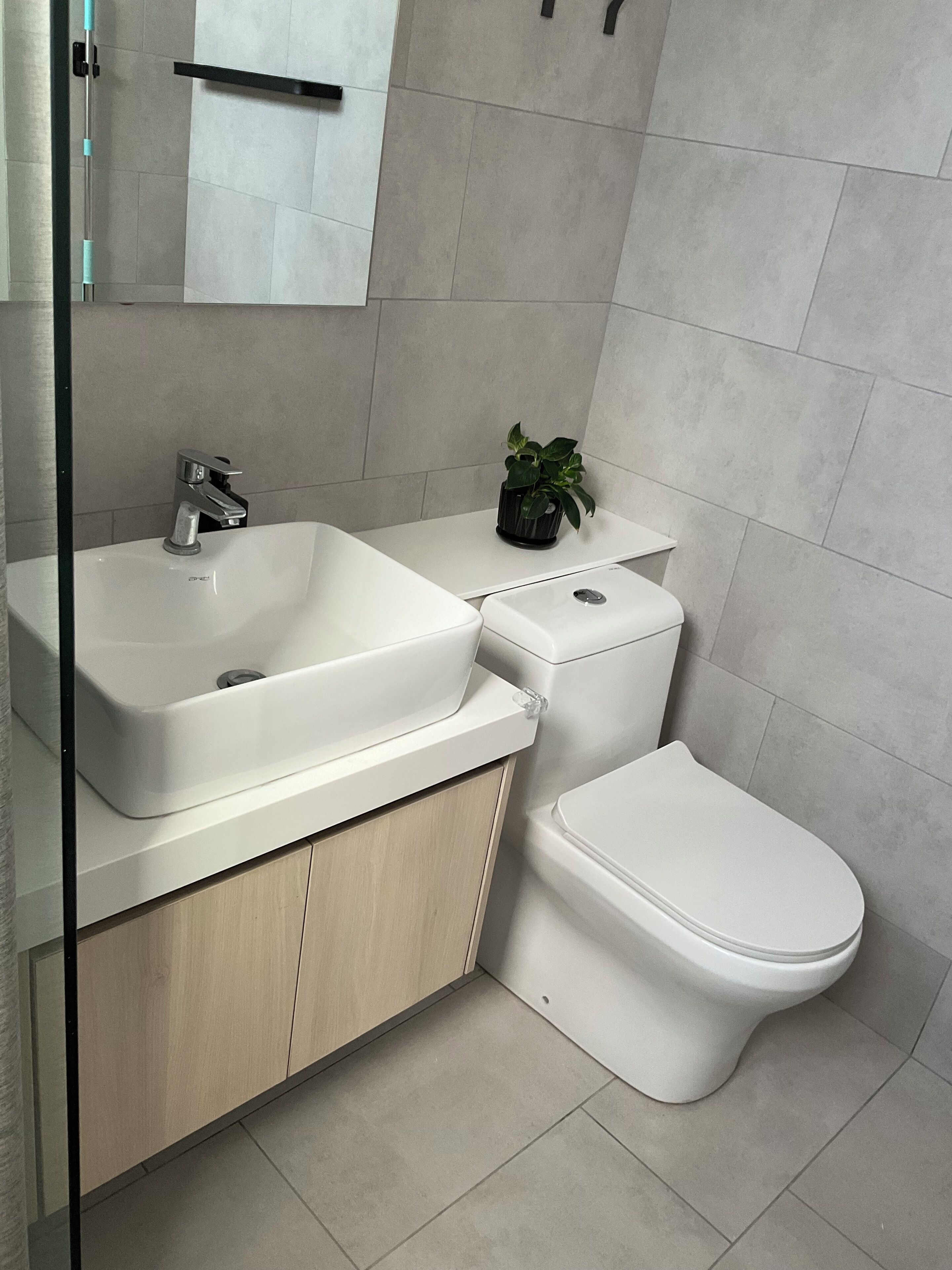 A modern bathroom with a white sink, toilet, and cabinet.