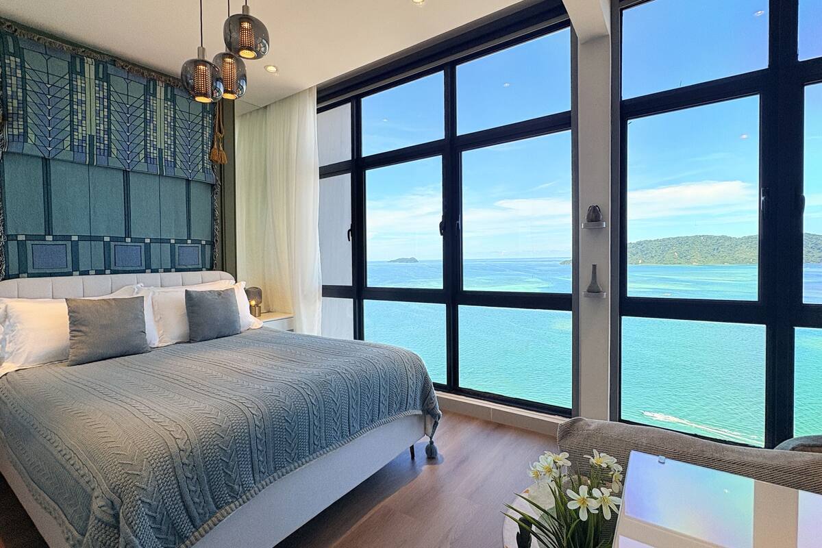 Een ruime slaapkamer met een groot bed, uitzicht op zee en een modern plafondontwerp.