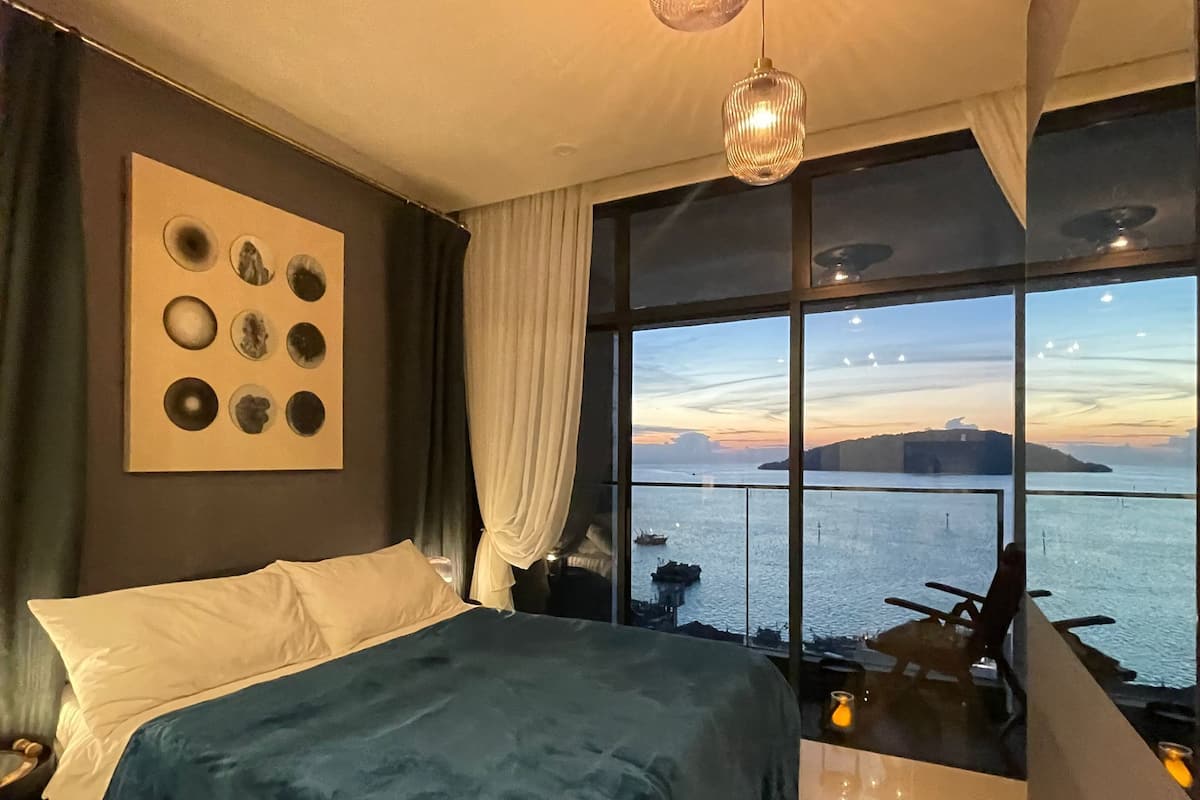 Een slaapkamer met een groot bed, uitzicht op zee en een muur met ronde decoraties.