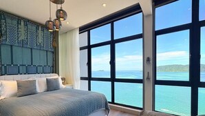 Una camera da letto con un letto grande, vista sul mare e una parete decorata.