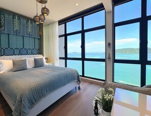Un dormitorio con una cama grande, vista al mar y una pared decorativa.