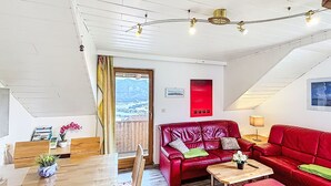 Ett mysigt vardagsrum med en röd lädersoffa, ett träbord och utsikt genom en dörr.