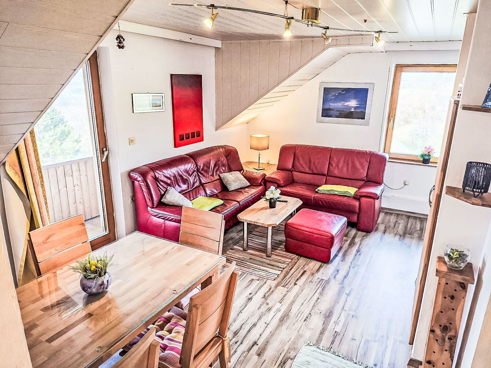 En hyggelig opholdsstue med en rød sofa, et træbord og en trappe.