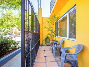 A small outdoor area with a yellow wall, a metal gate, and two plastic chairs. - Private Suite Ideal for Solo Travelers Or Couples (La Paz)
