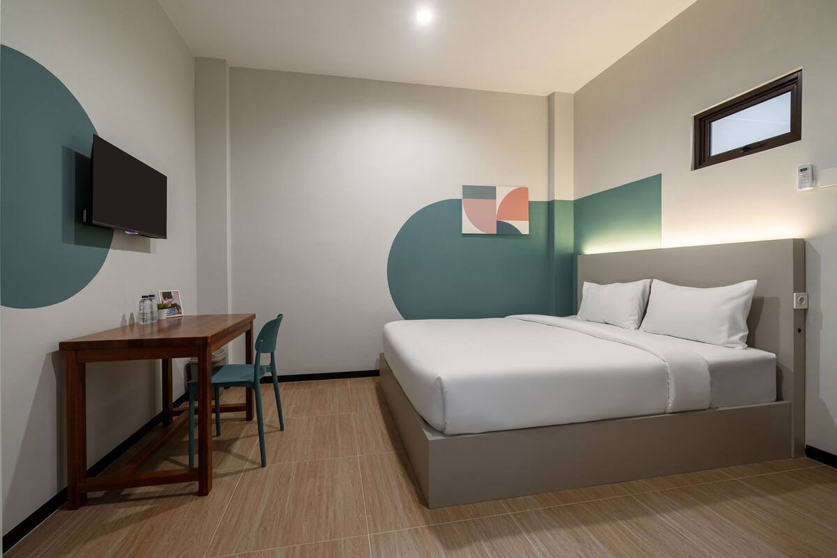 A modern hotel room with a bed, a desk, and a chair.