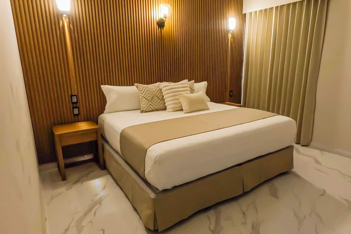 Un dormitorio moderno con una cama grande, paneles de madera y una mesita de noche.