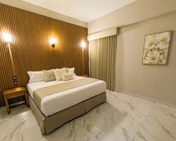 Un dormitorio con una cama grande, pared de paneles de madera, suelo de mármol y un cuadro de flores.
