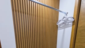 A corner of a room with a wooden slat wall, a black metal chair, a metal rack, and a wooden door. - Hotel JVD Inn - Tonalá Centro (Tonalá)