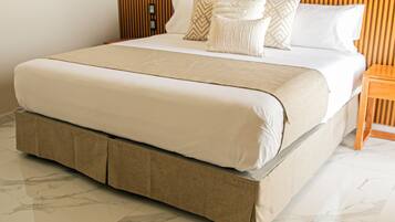 A bed with a wooden headboard, a beige bed skirt, and a white mattress.