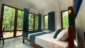 Une chambre avec un grand lit, une fenêtre et une vue sur les arbres.