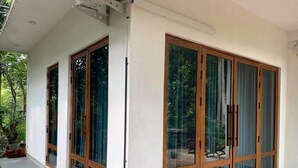 Un bâtiment moderne doté de grandes portes coulissantes en verre, d’un sol en béton et d’un petit espace extérieur aménagé avec des plantes.