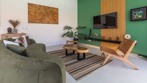 Olohuone, jossa on yksi seinä maalattu vihreällä korostusvärillä, seinälle asennettu televisio ja puinen sohvapöytä.