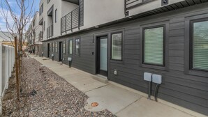 Un moderno edificio residencial de varios pisos con fachada limpia, ventanas amplias y un camino de grava.