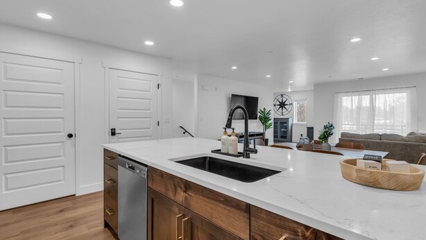 Una cocina moderna con una isla grande, muebles blancos y un grifo negro.