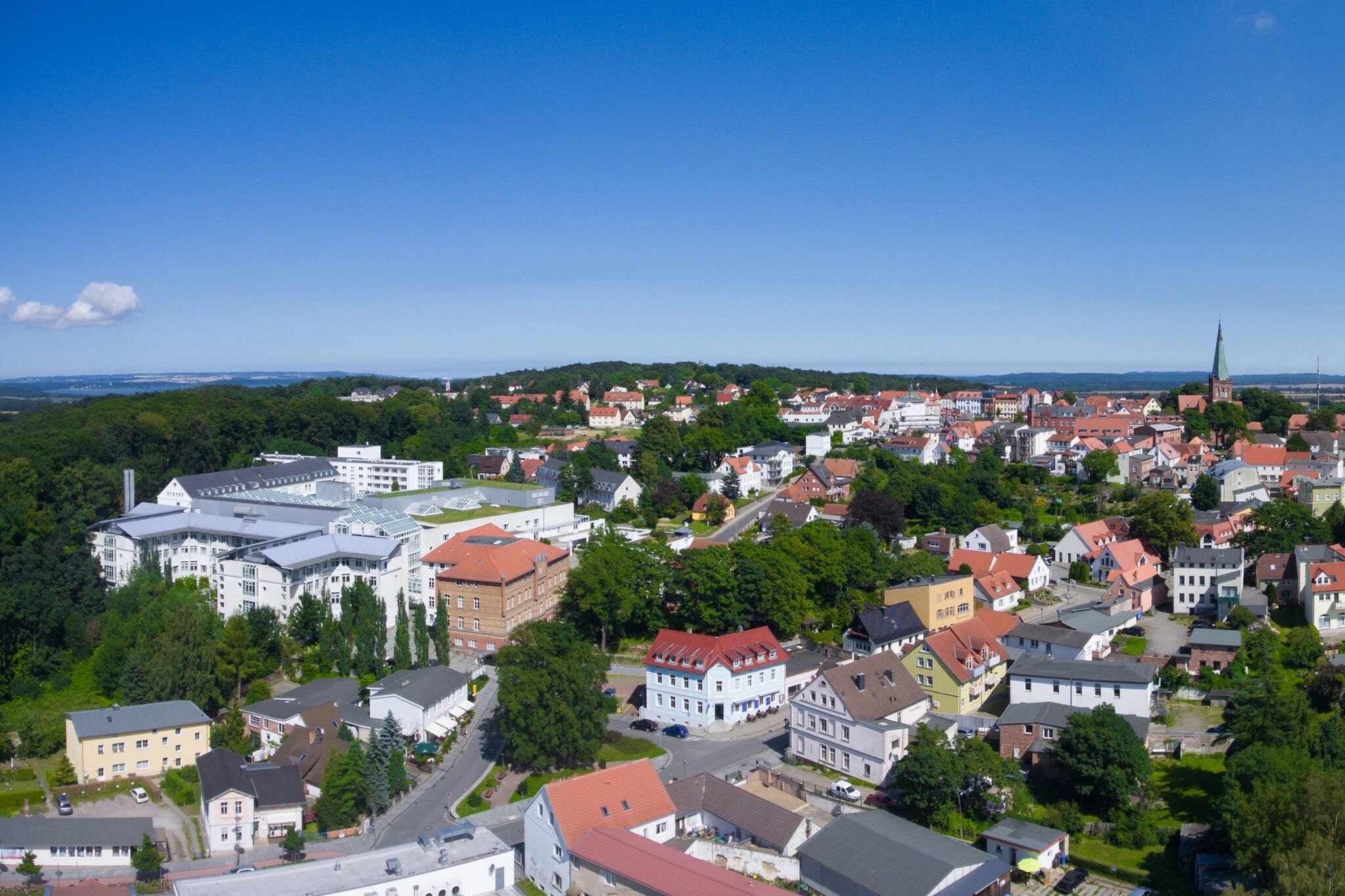 Ett flygbildsbild av en stad med en blandning av bostads- och affärsbyggnader, inklusive ett framträdande kyrktorn.