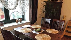 Uma mesa de jantar com jogos americanos trançados, um vaso e uma janela com vista para o verde.