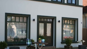 A building with three large windows, a door, and a small table with chairs outside. - Holiday flat at the market (Gingst)