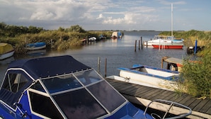 A calm waterway with boats docked at wooden piers. - Holiday flat at the market (Gingst)