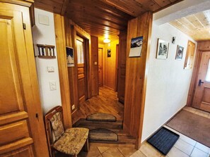Ein Korridor mit Holzboden, einer Bank, einer Tür und einem Kalender an der Wand.
