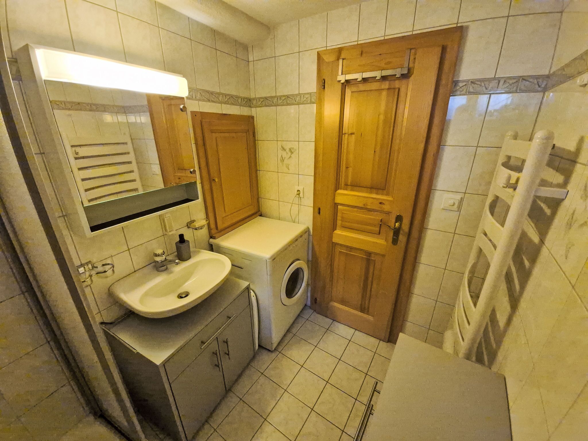 Un baño pequeño y funcional con lavamanos, espejo, inodoro y lavadora.