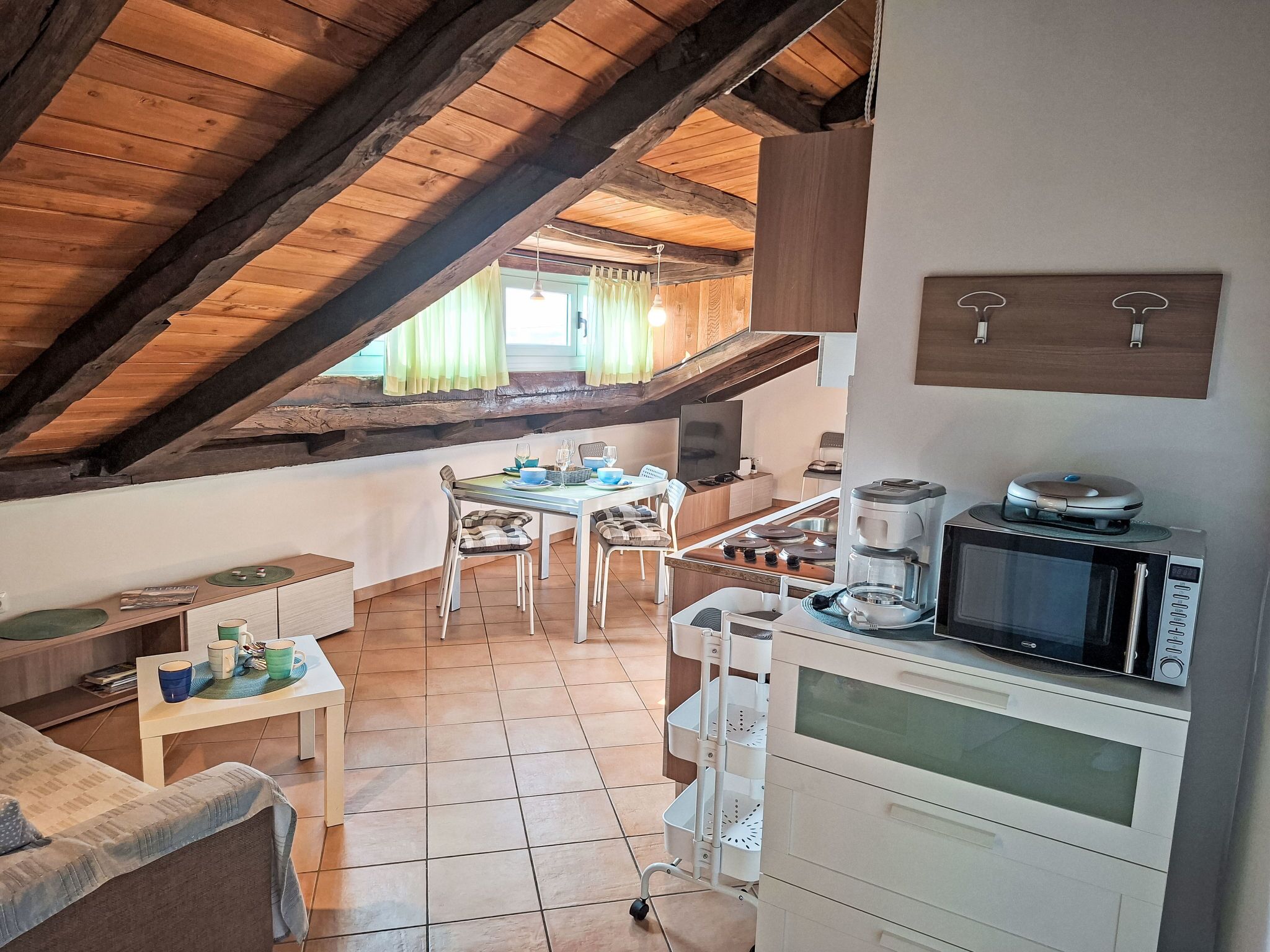 Une cuisine chaleureuse avec un plafond en bois, une table à manger avec des chaises, une machine à café et un four à micro-ondes.