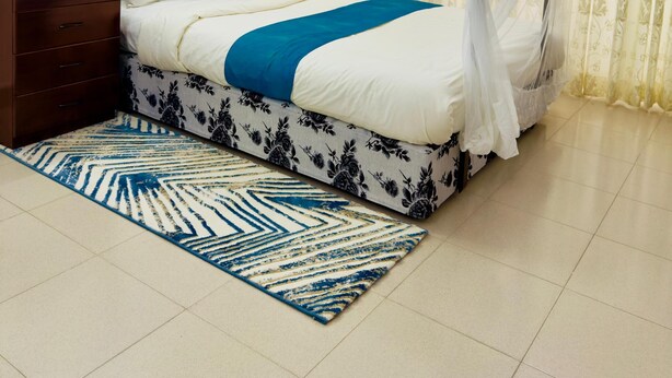 Une chambre à coucher avec un lit à baldaquin, une table de chevet, une lampe et un tapis à motifs.