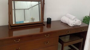 Une commode en bois avec un miroir, un tableau encadré et une serviette enroulée.