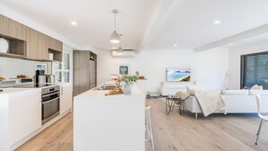 Una cocina moderna con una isla central, armarios de madera y un comedor con sofá y mesa.