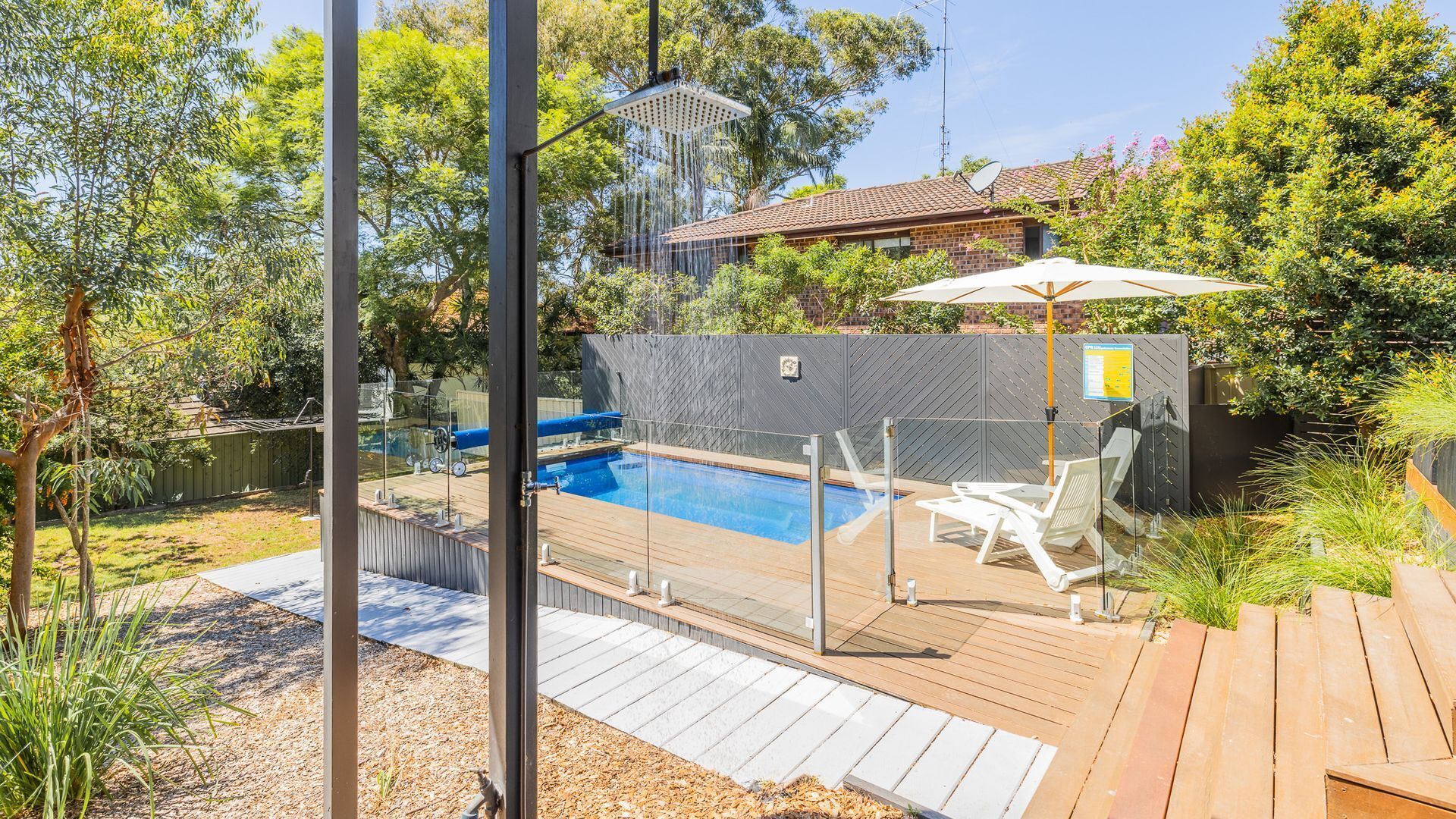 Un patio trasero con piscina, terraza y zona de patio cubierta.