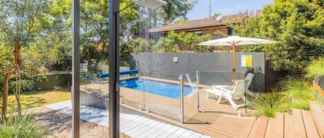 Un patio trasero con piscina, terraza y zona de patio cubierta.