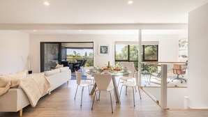 Un interior moderno con comedor, sofá y balcón con vistas.