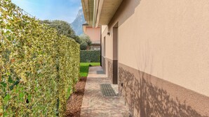 A narrow pathway with a hedge on one side and a building on the other. - Garda Oasis and Horizon by Interhome (Riva del Garda)
