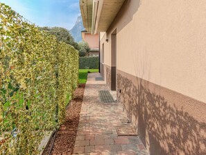A narrow pathway with a hedge on one side and a building on the other. - Garda Oasis and Horizon by Interhome (Riva del Garda)